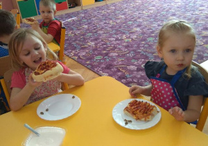 Dzieci jedzą przyrządzoną pizzę