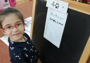 Dziewczynka przy tablicy rozwiązuje zadanie matematyczne