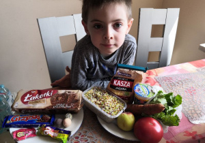 Chłopiec prezentuje zdrowe i niezdrowe produkty