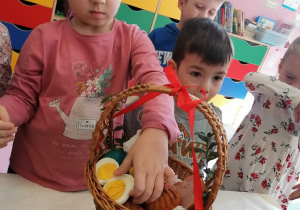 Dziewczynka wkłada do koszyczka jajko