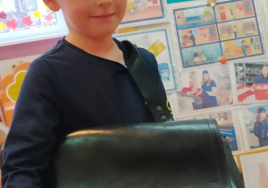 Chłopiec w czapce z torbą listonosza