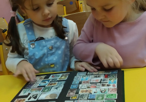 Dziewczynki oglądają klaser ze znaczkami