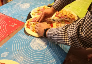 Dzieci wykonują własnoręczną pizzę