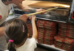 Dziewczynka wkłada pizzę do pieca