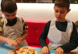 Chłopcy komponują własną pizzę
