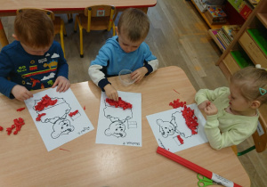 Dzieci wyklejają biało - czerwone misie