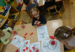 Dzieci wyklejają biało - czerwone misie