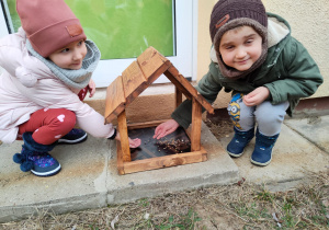 Dzieci wsypują ziarenka do karmnika
