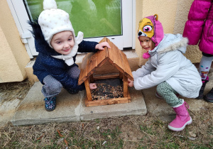 Dzieci wsypują ziarenka do karmnika