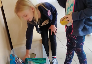 Dziewczynki wkładają puszki dla zwierząt ze schroniska