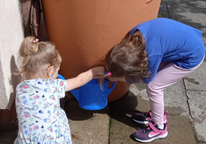 Dzieci nalewają deszczówkę do konewki