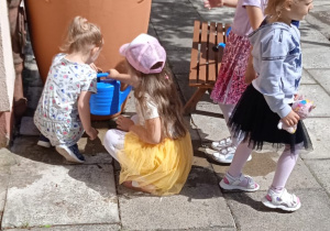 Dzieci nalewają deszczówkę do konewki
