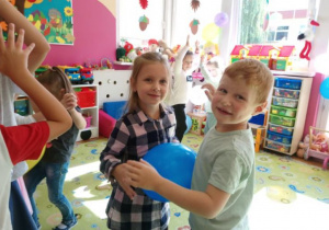 Chłopiec i dziewczynka tańczą z balonem