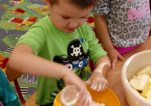 Chłopiec dosypuje mąki do miski