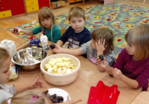 Dzieci siedzą i trzymają owoce