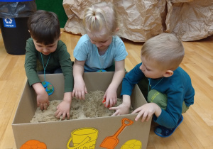 Maluchy szukają foremek w piasku