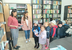 Dzieci otrzymują cukierki od pań z biblioteki